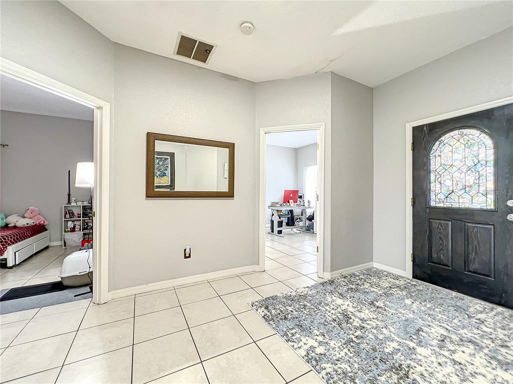 An entryway features light tile flooring, a dark wood front door, and two arched doorways — 501 SUMMER PLACE LOOP, CLERMONT, FL