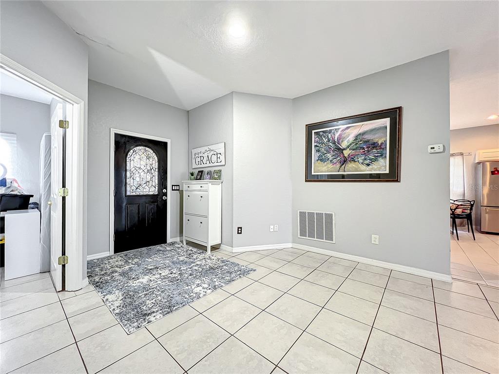 An entryway features light gray walls, tiled flooring, a black front door, and a framed painting — 501 SUMMER PLACE LOOP, CLERMONT, FL