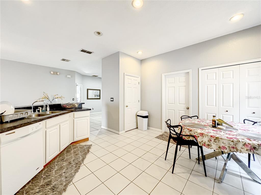 A kitchen with white cabinets, dark countertops, and a dining area with a floral tablecloth — 501 SUMMER PLACE LOOP, CLERMONT, FL