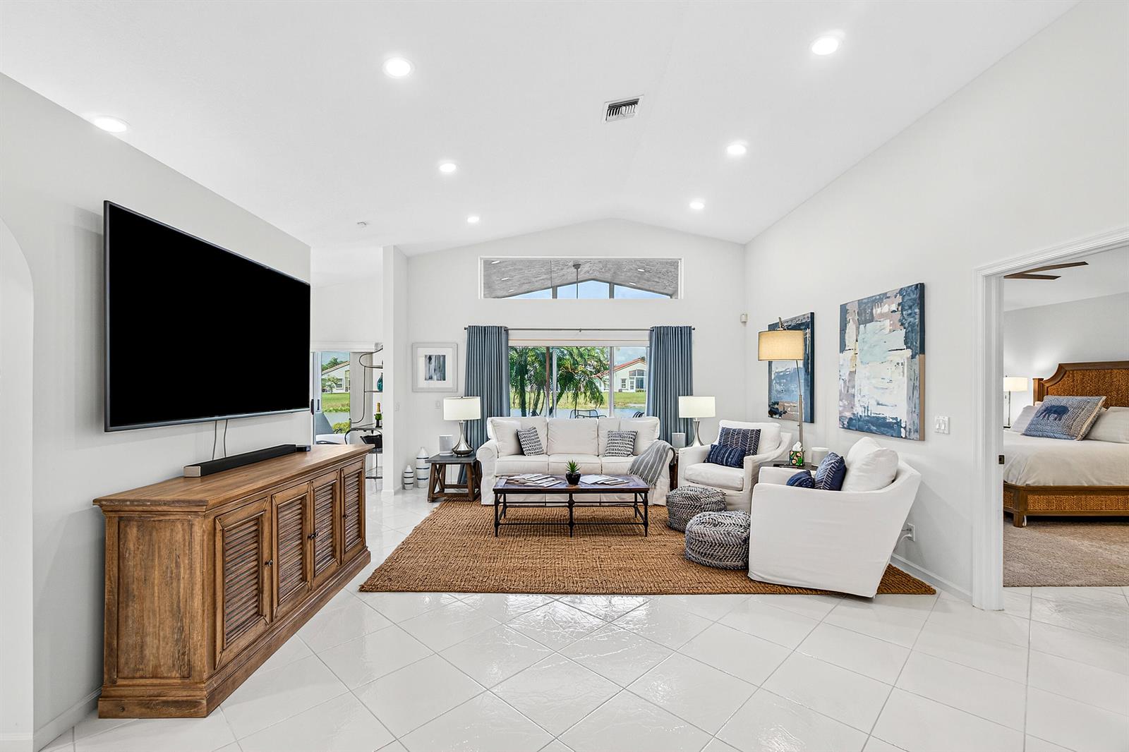 A living room with white tile floors, a large television, and a view of water — 6594 Sun River Road, Boynton Beach FL 33437, BOYNTON BEACH, FL