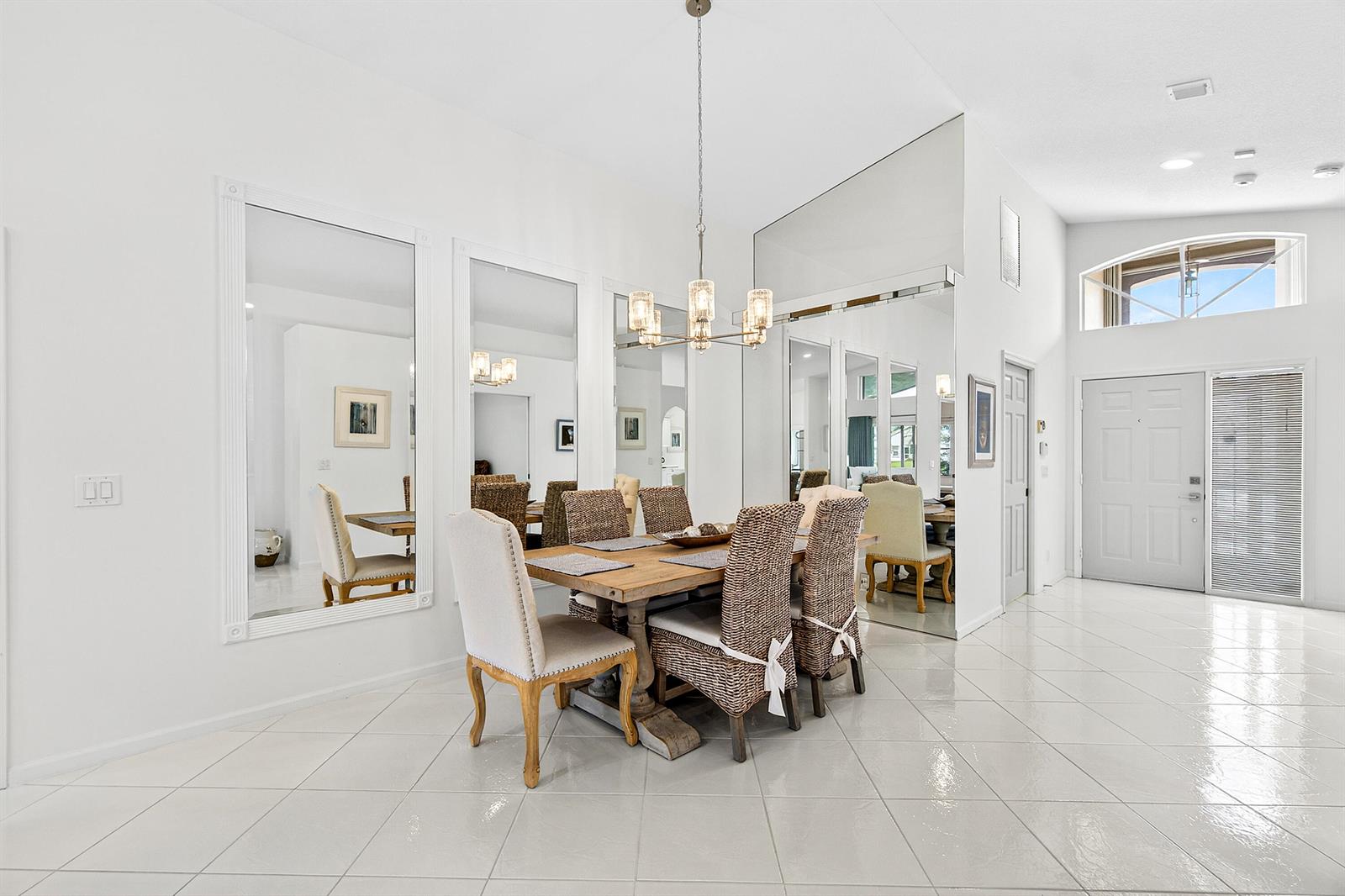 A dining room features a wooden table, woven chairs, mirrored walls, and white tile flooring — 6594 Sun River Road, Boynton Beach FL 33437, BOYNTON BEACH, FL