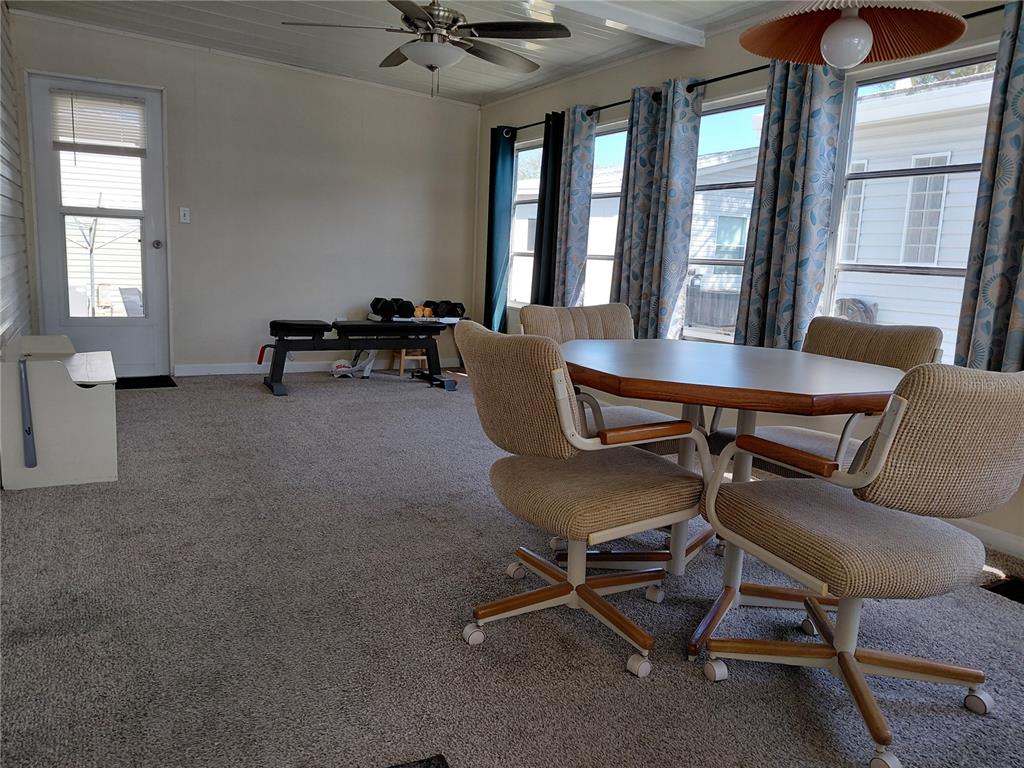 A sunroom features carpeted flooring, a dining set, a ceiling fan, and a workout bench — 1001 STARKEY ROAD UNIT 704, LARGO, FL