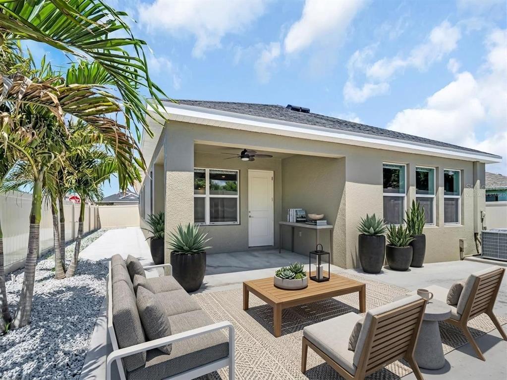 A covered patio features outdoor furniture, potted plants, and a concrete floor under a blue sky — 1461 N RIVER CIRCLE, TARPON SPRINGS, FL