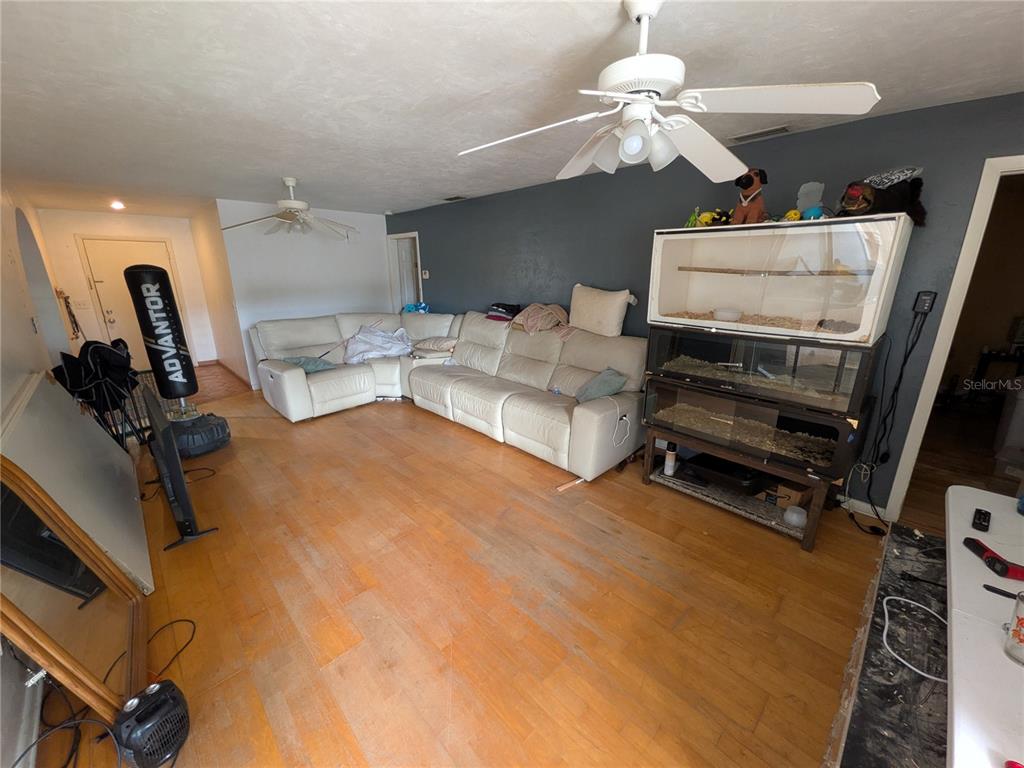 A living room features a white sectional sofa, wood flooring, and a large reptile enclosure — 7167 COLUMBIA CIRCLE, FORT MYERS, FL