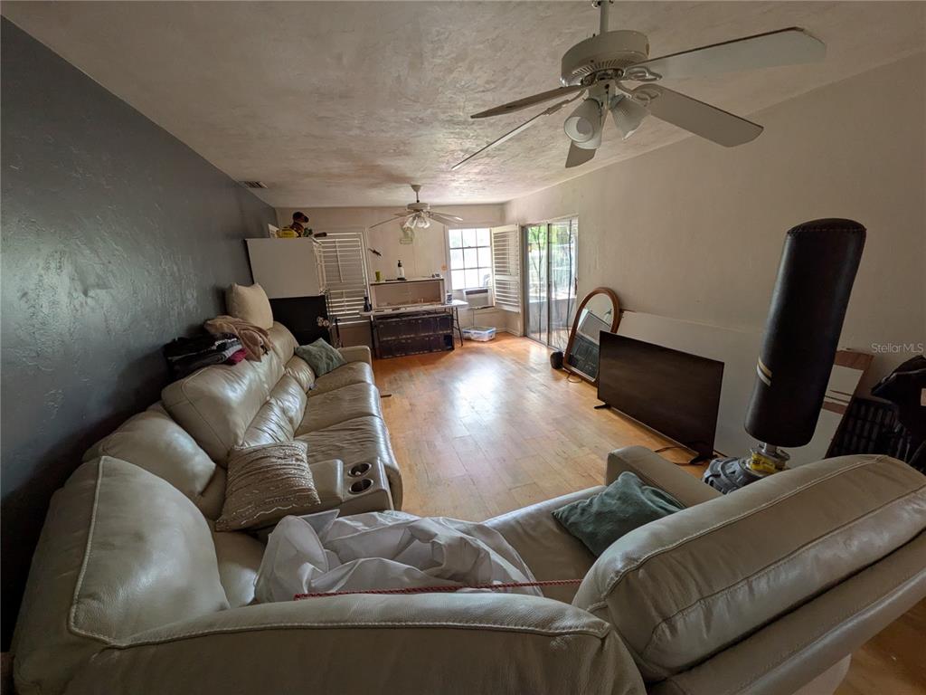 A living room with light wood flooring, a large sectional sofa, and a ceiling fan — 7167 COLUMBIA CIRCLE, FORT MYERS, FL