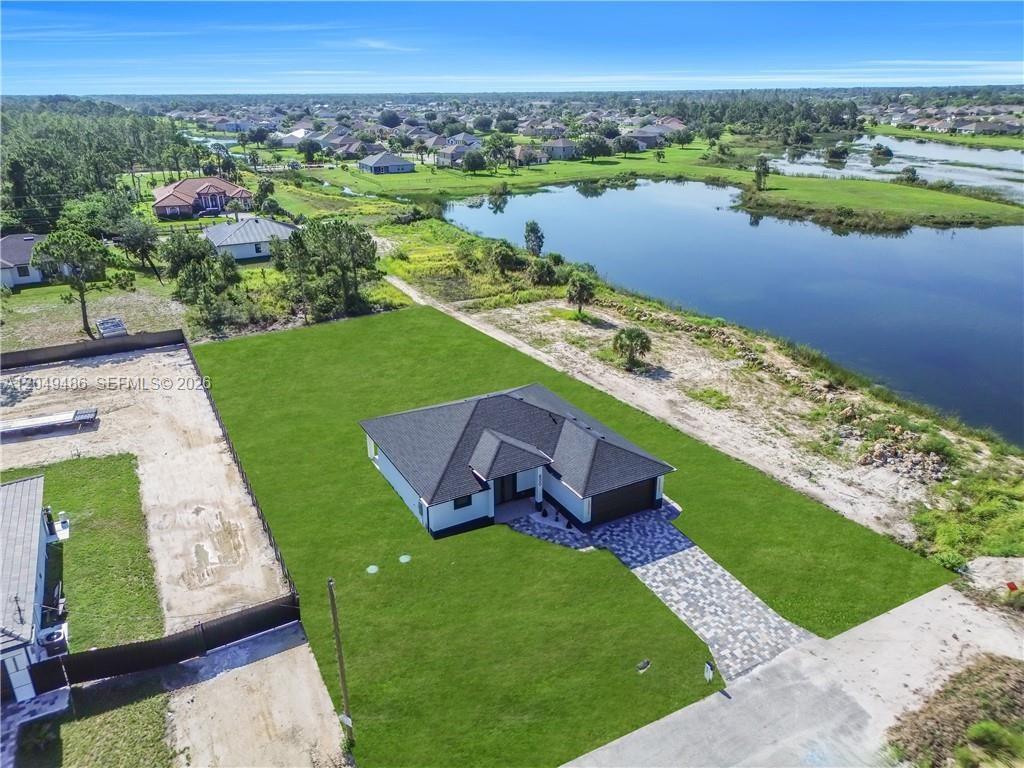 An aerial view shows a single-story house with a paved driveway on a grassy lot — 800 Pine Ave, Lehigh Acres FL 33972, LEHIGH ACRES, FL