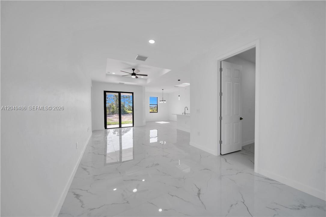 A bright, open-concept living area features white marble-style flooring and a tray ceiling — 800 Pine Ave, Lehigh Acres FL 33972, LEHIGH ACRES, FL