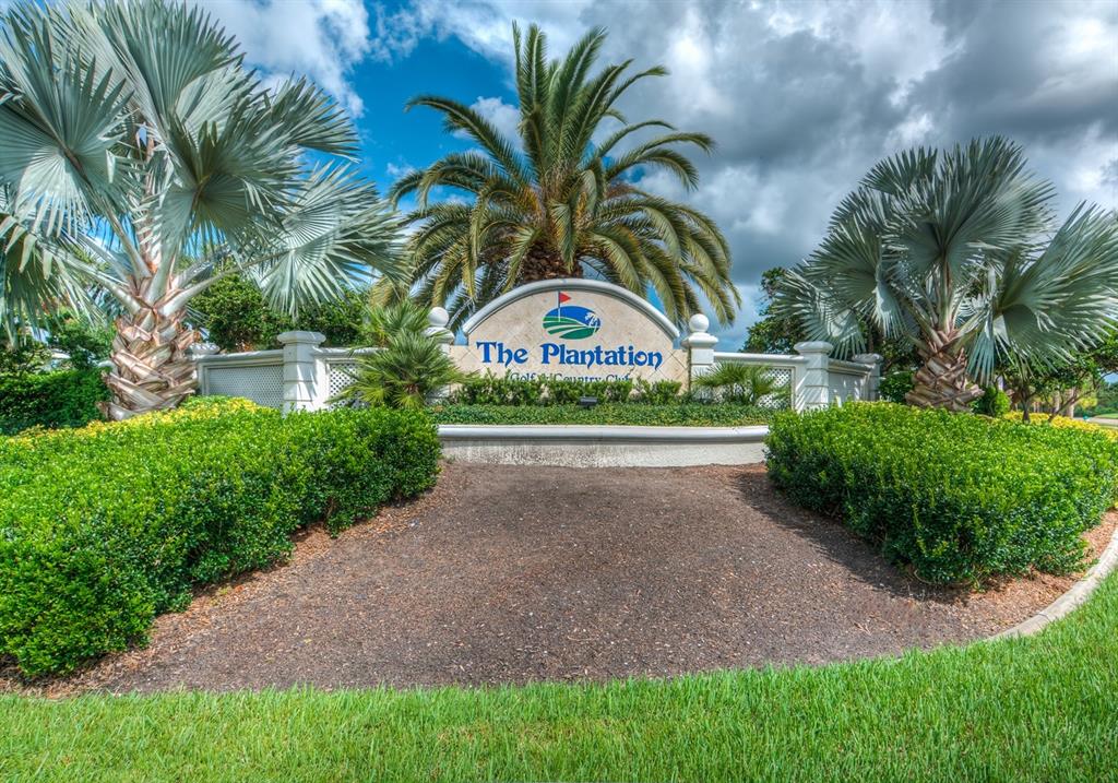 A sign for The Plantation Golf & Country Club stands behind manicured hedges and palm trees — 130 SOUTHAMPTON PLACE UNIT 360, VENICE, FL