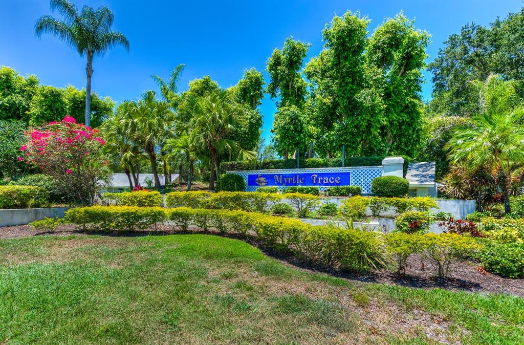A blue sign reading Myrtle Trace stands behind landscaped bushes and trees under a clear sky — 130 SOUTHAMPTON PLACE UNIT 360, VENICE, FL