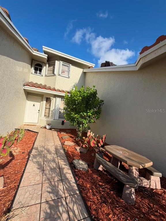 A stone walkway leads to a house entrance with a stone picnic table nearby — 7380 PINEWALK DRIVE S UNIT 37-8, MARGATE, FL