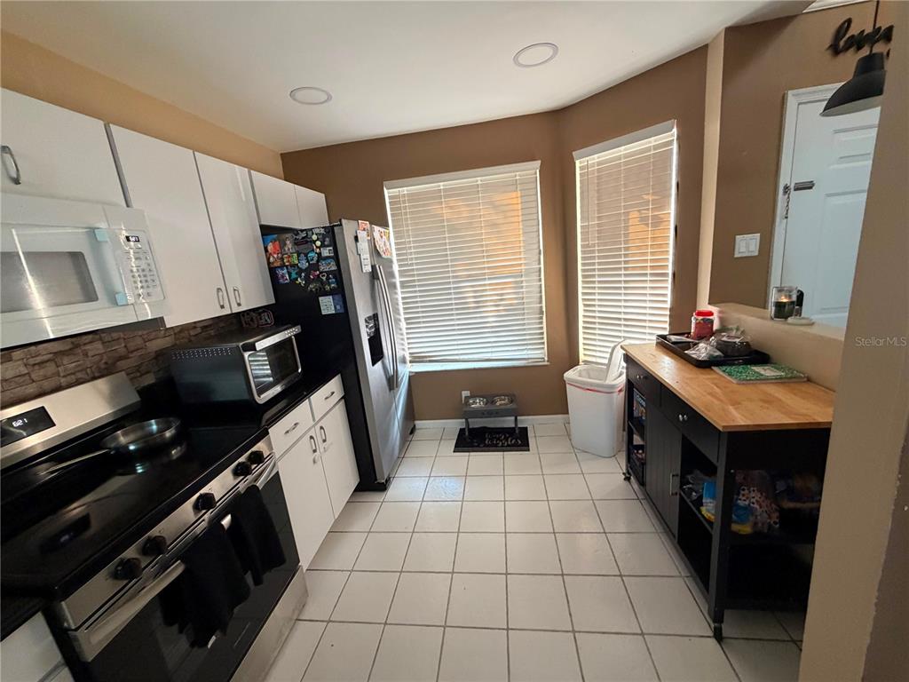 A kitchen with white cabinets, black appliances, tile flooring, and a wooden kitchen island — 7380 PINEWALK DRIVE S UNIT 37-8, MARGATE, FL