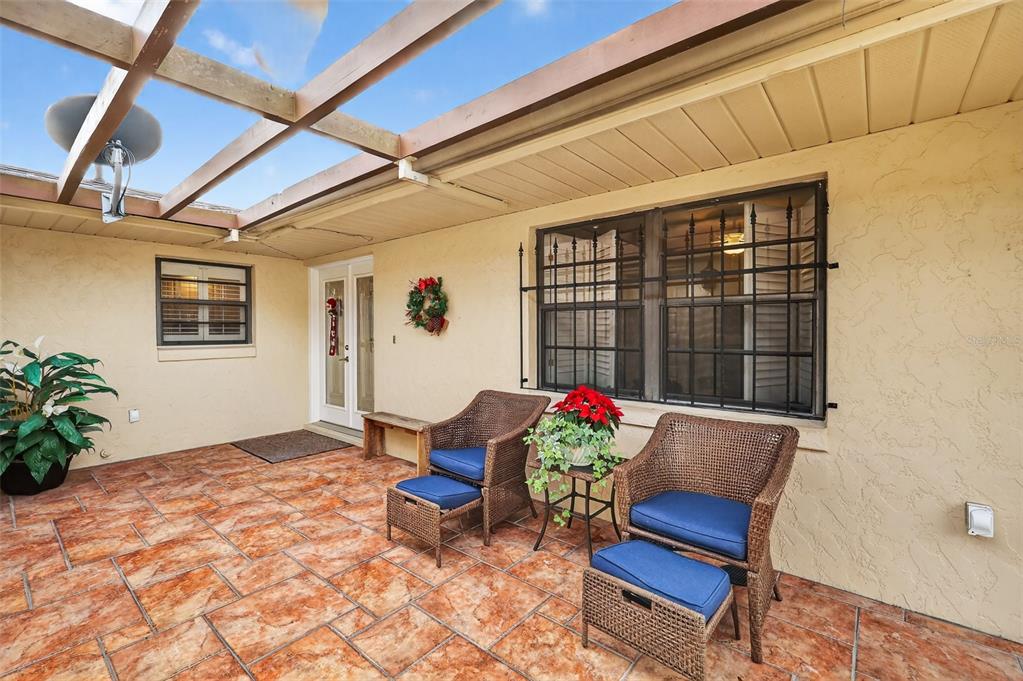 A patio with tiled flooring, a wooden pergola, and two wicker chairs with blue cushions — 100 S TREMAIN STREET UNIT F1, MOUNT DORA, FL