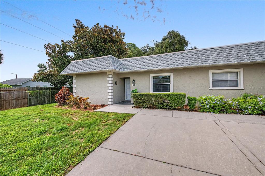A single-story house with a gray stucco exterior, a shingled roof, and a concrete driveway — 3526 TEESIDE DRIVE, NEW PORT RICHEY, FL