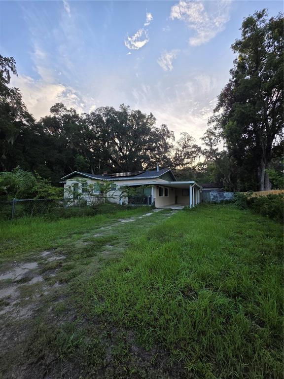 A single-story house with a carport and solar panels sits on a large grassy lot — 11647 SE 60TH AVENUE, BELLEVIEW, FL