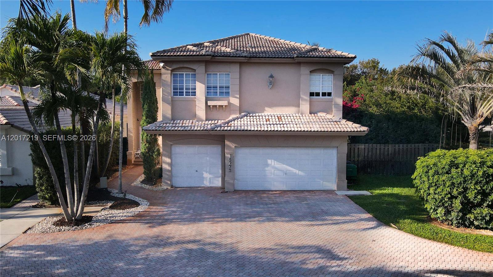 A two-story suburban house features a tiled roof, beige stucco walls, and a paved driveway — 10773 NW 73rd Ter, Doral FL 33178, DORAL, FL