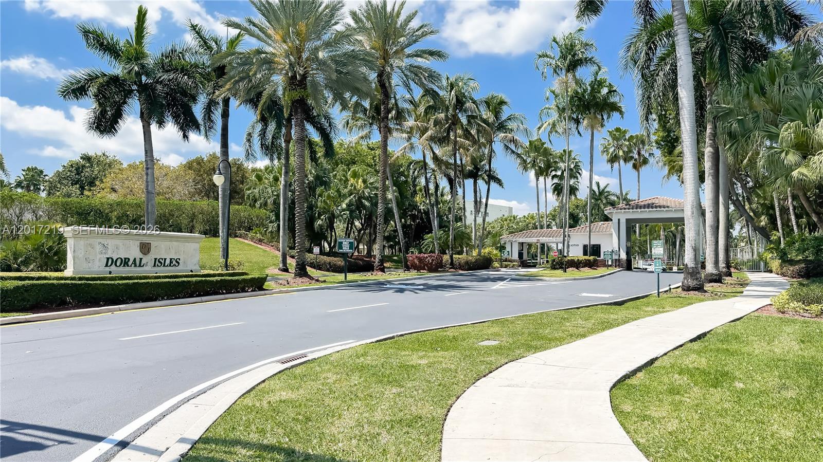 The entrance to the Doral Isles community features a stone sign, palm trees, and gatehouse — 10773 NW 73rd Ter, Doral FL 33178, DORAL, FL