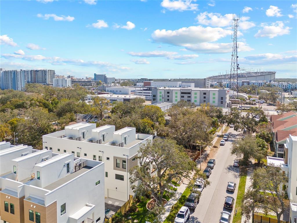 An aerial view shows modern townhomes, a street with parked cars, and a distant stadium — 301 15TH STREET N, ST PETERSBURG, FL