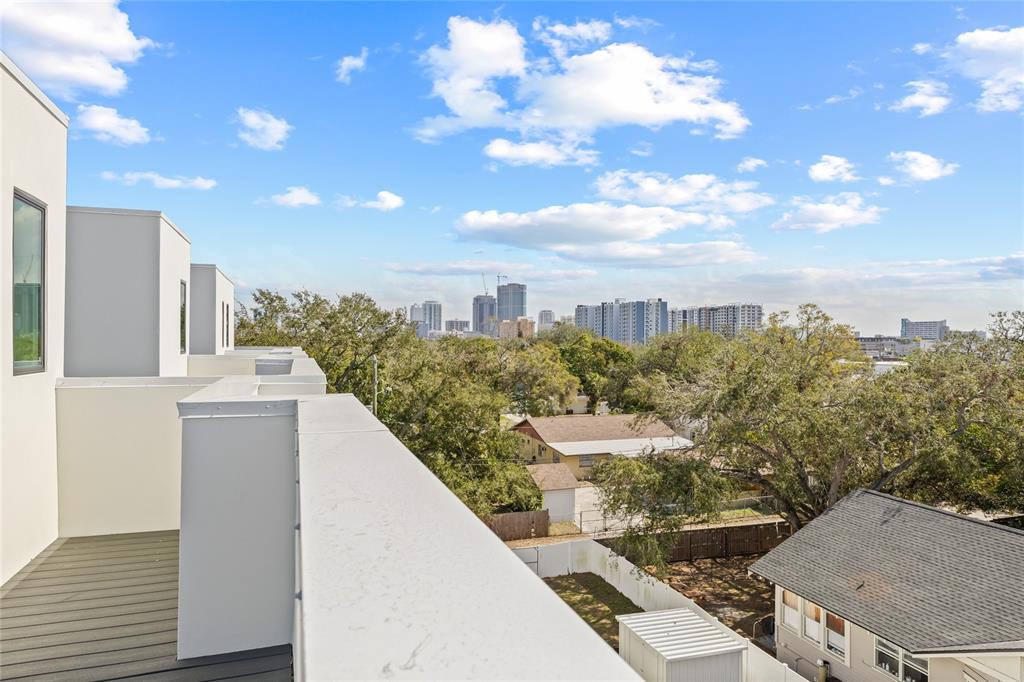 A view from a modern rooftop balcony overlooking trees, houses, and a distant city skyline — 301 15TH STREET N, ST PETERSBURG, FL