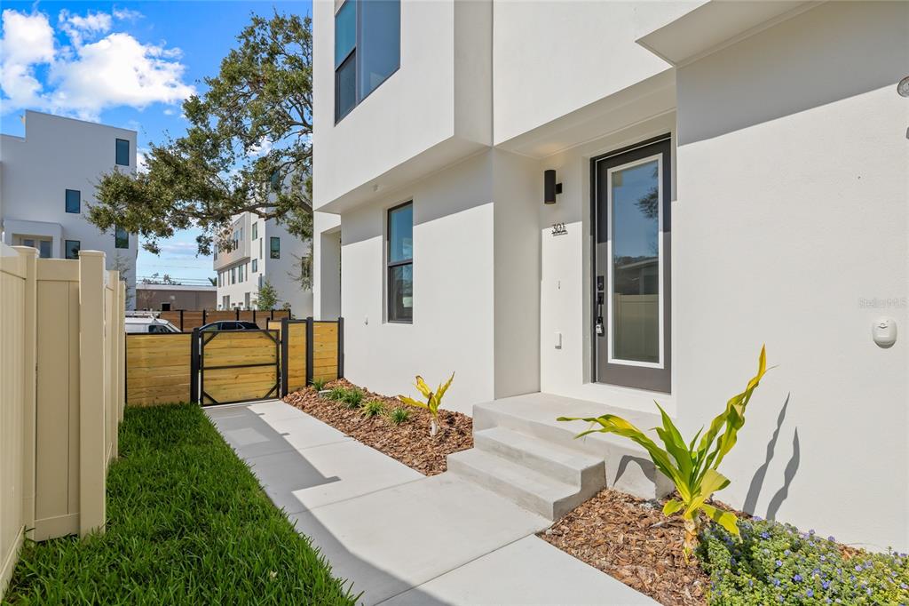 A modern white townhouse exterior features a front entrance with concrete steps and landscaping — 301 15TH STREET N, ST PETERSBURG, FL