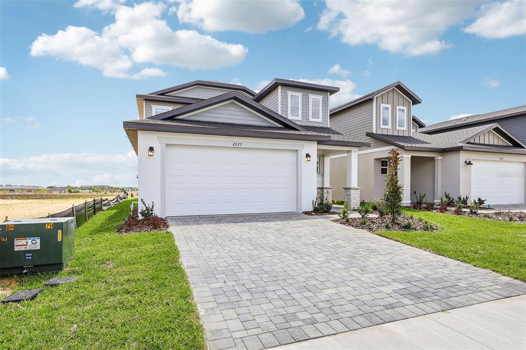 A two-story house with a white garage, gray siding, and a paved driveway — 2277 HEN ROAD, MINNEOLA, FL