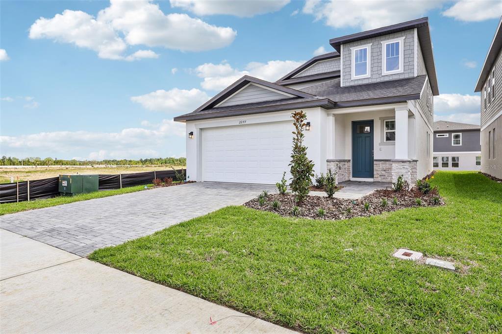 A two-story house with a white garage, blue front door, and gray shingled roof — 2277 HEN ROAD, MINNEOLA, FL