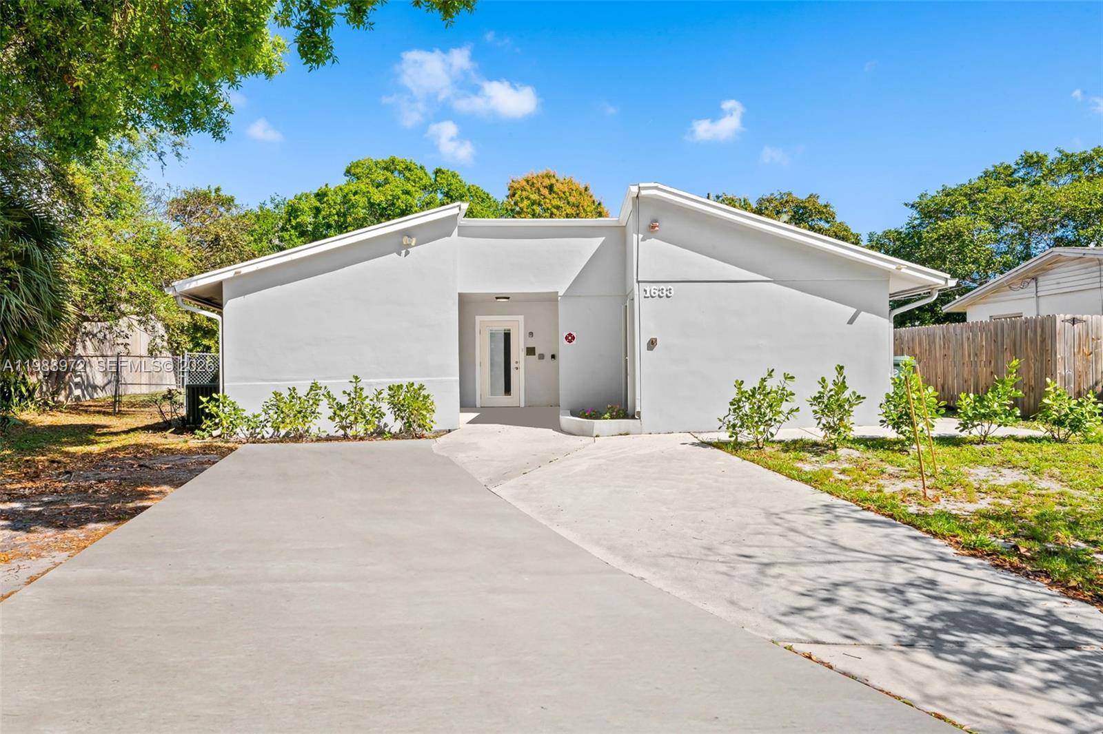 A single-story house with a white exterior, a concrete driveway, and a central recessed entryway — 1633 NW 4th St, Boca Raton FL 33486, BOCA RATON, FL