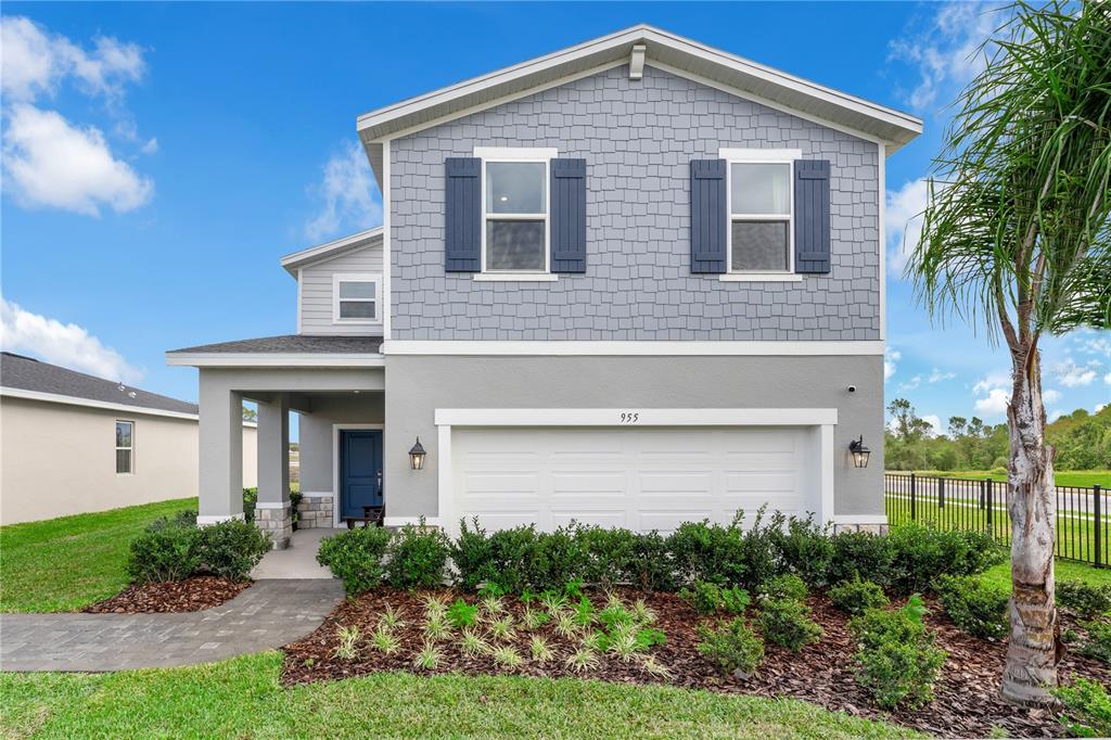 A two-story house with a gray shingle facade, blue shutters, and a two-car garage — 3842 SENNA WAY, TAVARES, FL