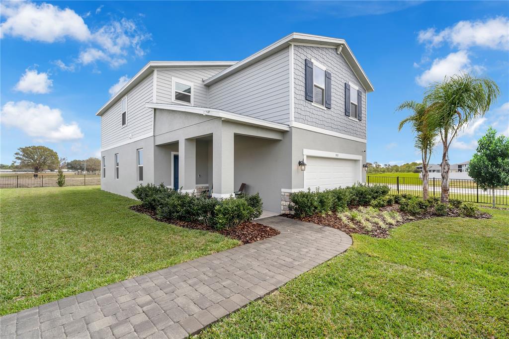 A two-story house with gray siding, a stone-accented garage, and a paved walkway — 3842 SENNA WAY, TAVARES, FL