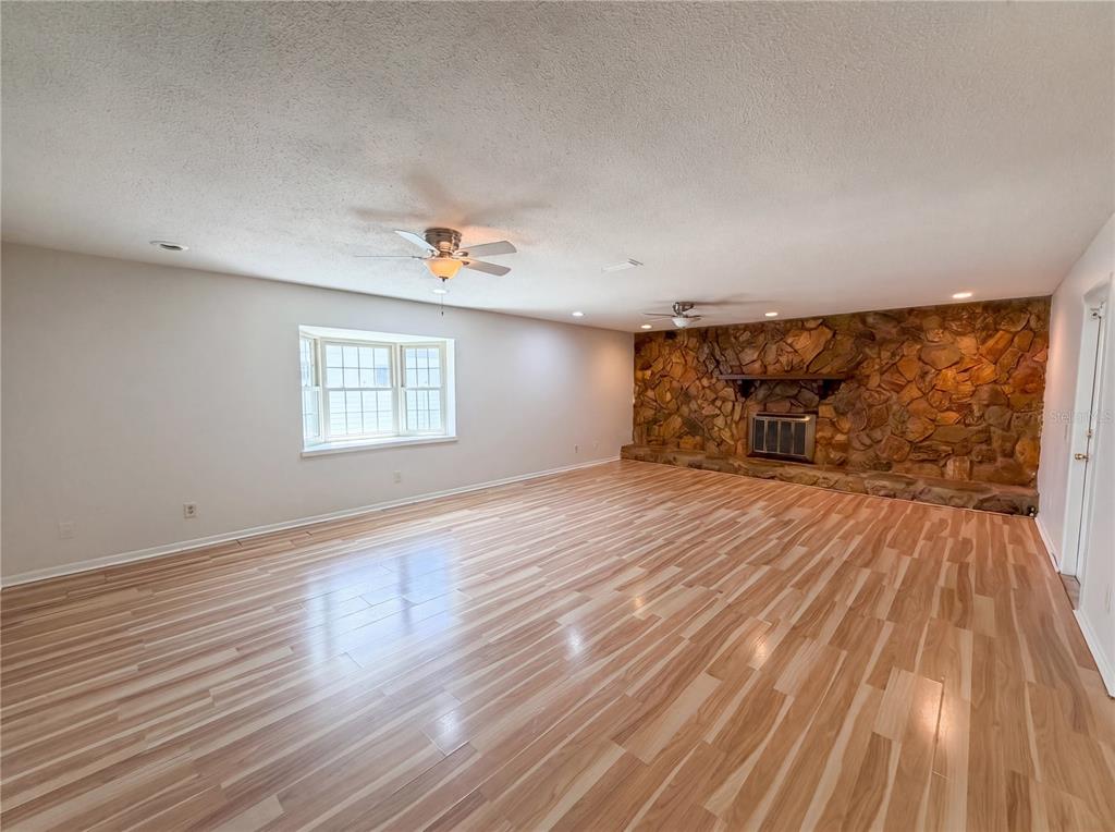 A spacious living room features light wood-look flooring, a stone fireplace, and a bay window — 2534 VICTARRA CIRCLE, LUTZ, FL
