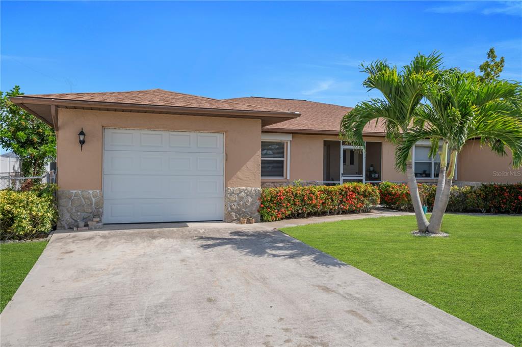 A single-story house with a tan stucco exterior, stone accents, a garage, and a palm tree — 836 SW TRAFALGAR PKWY, CAPE CORAL, FL