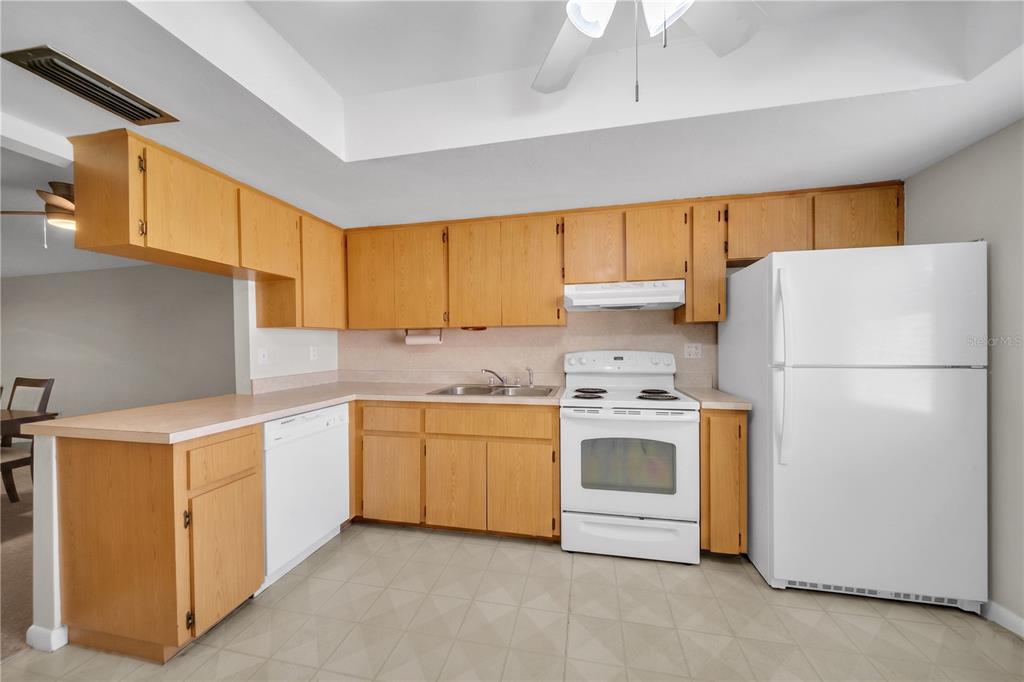 A kitchen features light wood cabinets, white appliances, and a laminate countertop — 836 SW TRAFALGAR PKWY, CAPE CORAL, FL