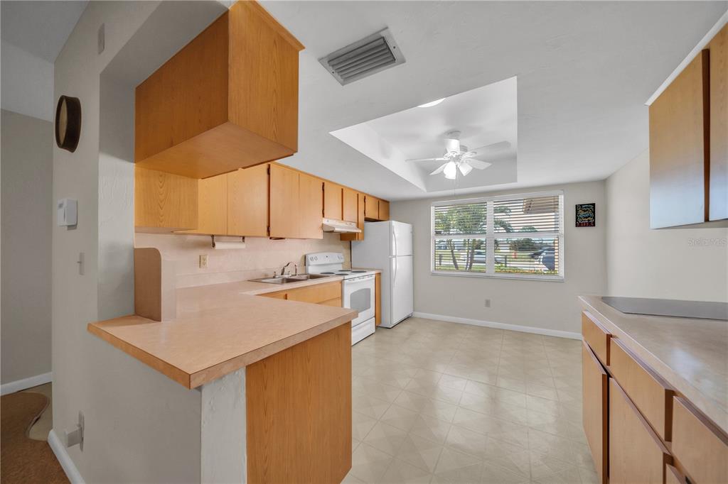 A kitchen features light wood cabinets, laminate countertops, white appliances, and a tray ceiling — 836 SW TRAFALGAR PKWY, CAPE CORAL, FL