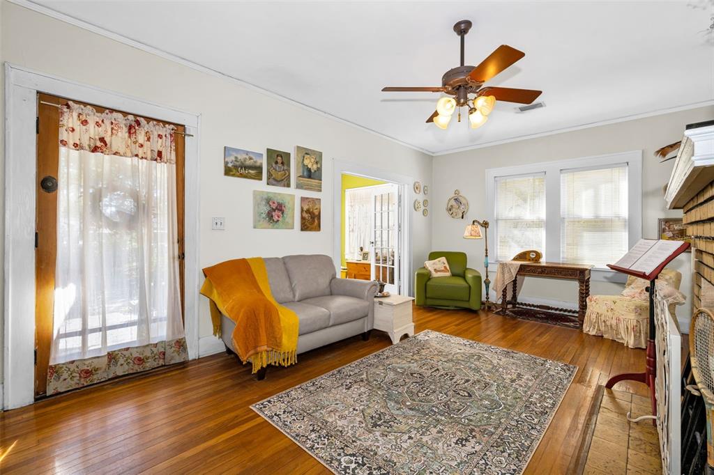 A living room features hardwood floors, a gray sofa, a green armchair, and a fireplace — 3411 W BAY AVENUE, TAMPA, FL