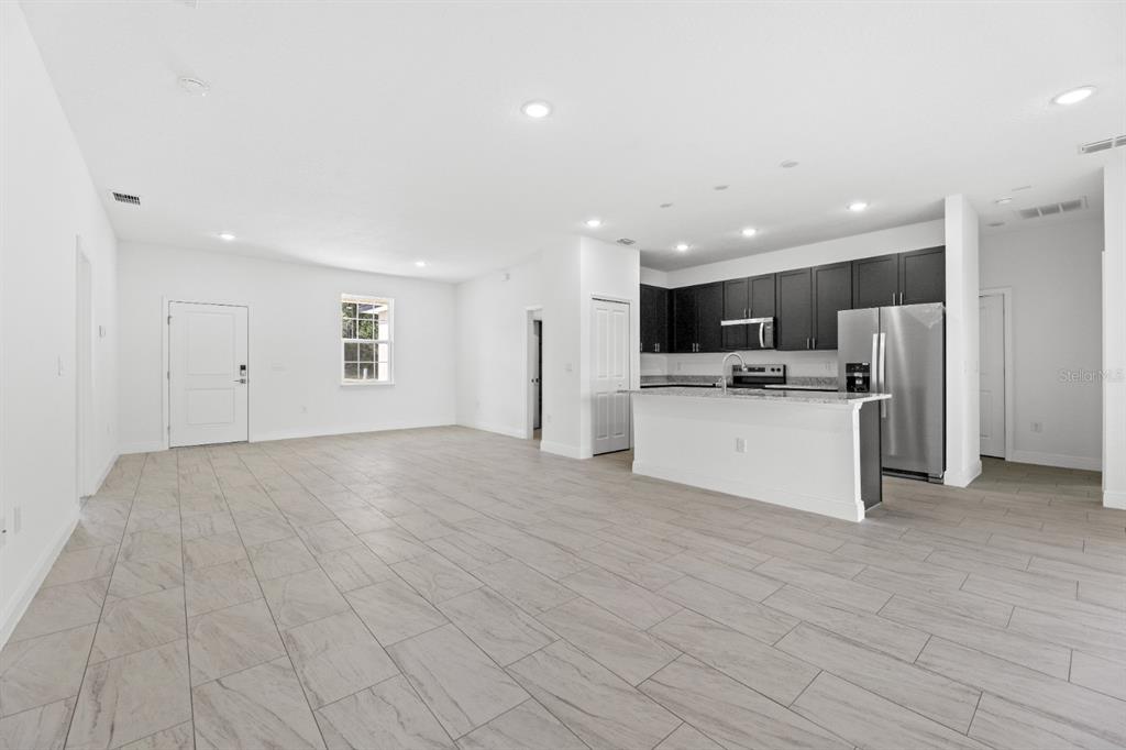 An open-concept living area features light-colored tile flooring, white walls, and a modern kitchen — 2744 W REDGATE DRIVE, DUNNELLON, FL