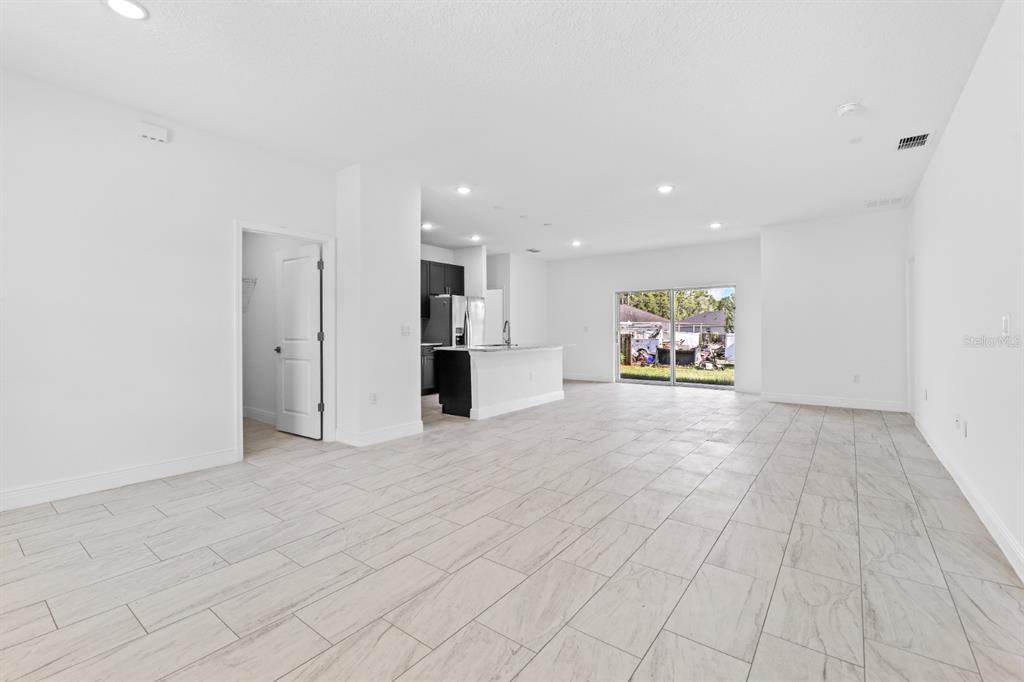 An open-concept living area features light-colored tile flooring, a kitchen island, and sliding glass doors — 2744 W REDGATE DRIVE, DUNNELLON, FL