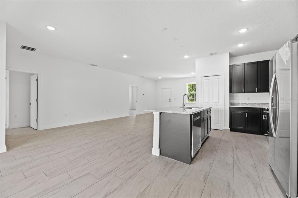 A kitchen with a dark island and cabinets, granite countertops, and light tile flooring — 2744 W REDGATE DRIVE, DUNNELLON, FL