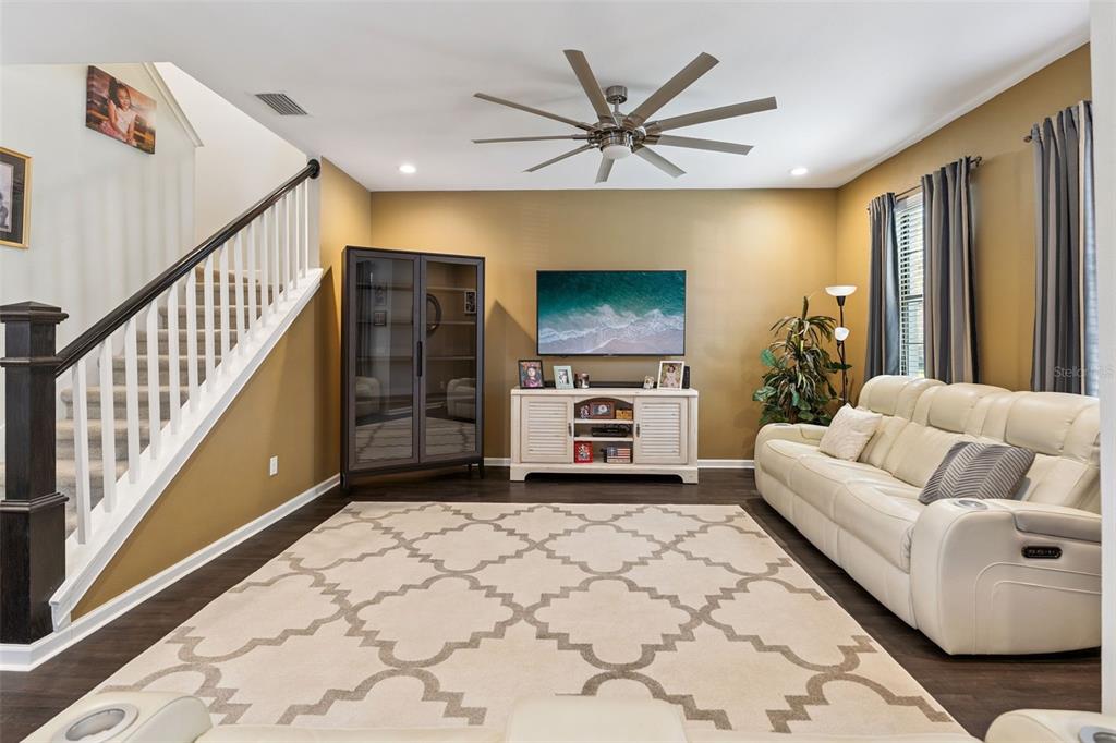 A living room features a white sofa, a television on a console, and a staircase — 5714 COLONY GLEN ROAD, LITHIA, FL