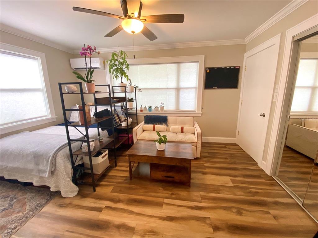 A studio room features wood-look flooring, a bed, a small sofa, and a ceiling fan — 828 22ND AVENUE N Apt. West, ST PETERSBURG, FL