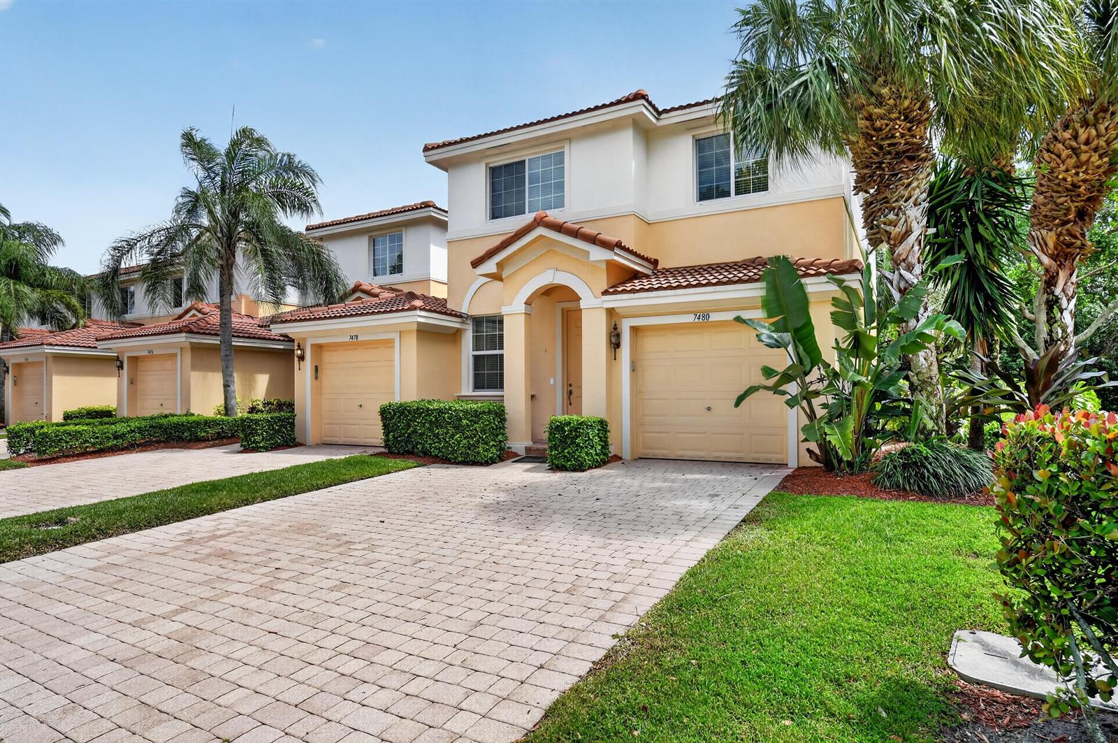 A two-story stucco townhouse with a paved driveway, a two-car garage, and palm trees — 7480 Sarentino Lane, Boynton Beach FL 33437, BOYNTON BEACH, FL