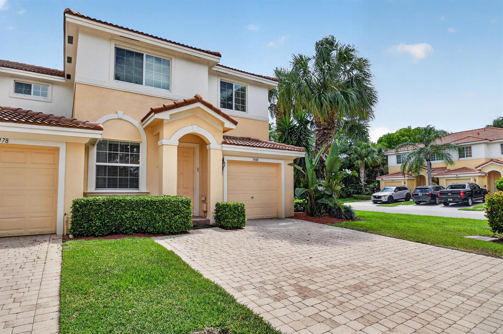 A two-story beige townhouse with a paved driveway, a garage, and a small front lawn — 7480 Sarentino Lane, Boynton Beach FL 33437, BOYNTON BEACH, FL