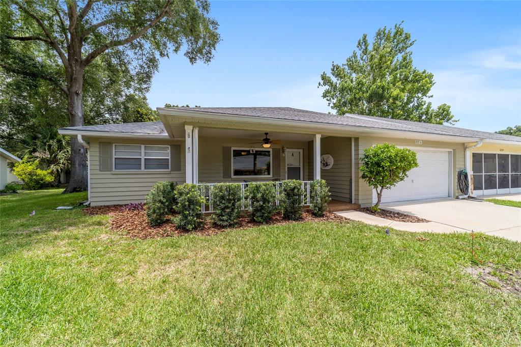 A single-story house with light green siding, a covered front porch, and an attached garage — 8707 SW 95TH LANE UNIT A, OCALA, FL
