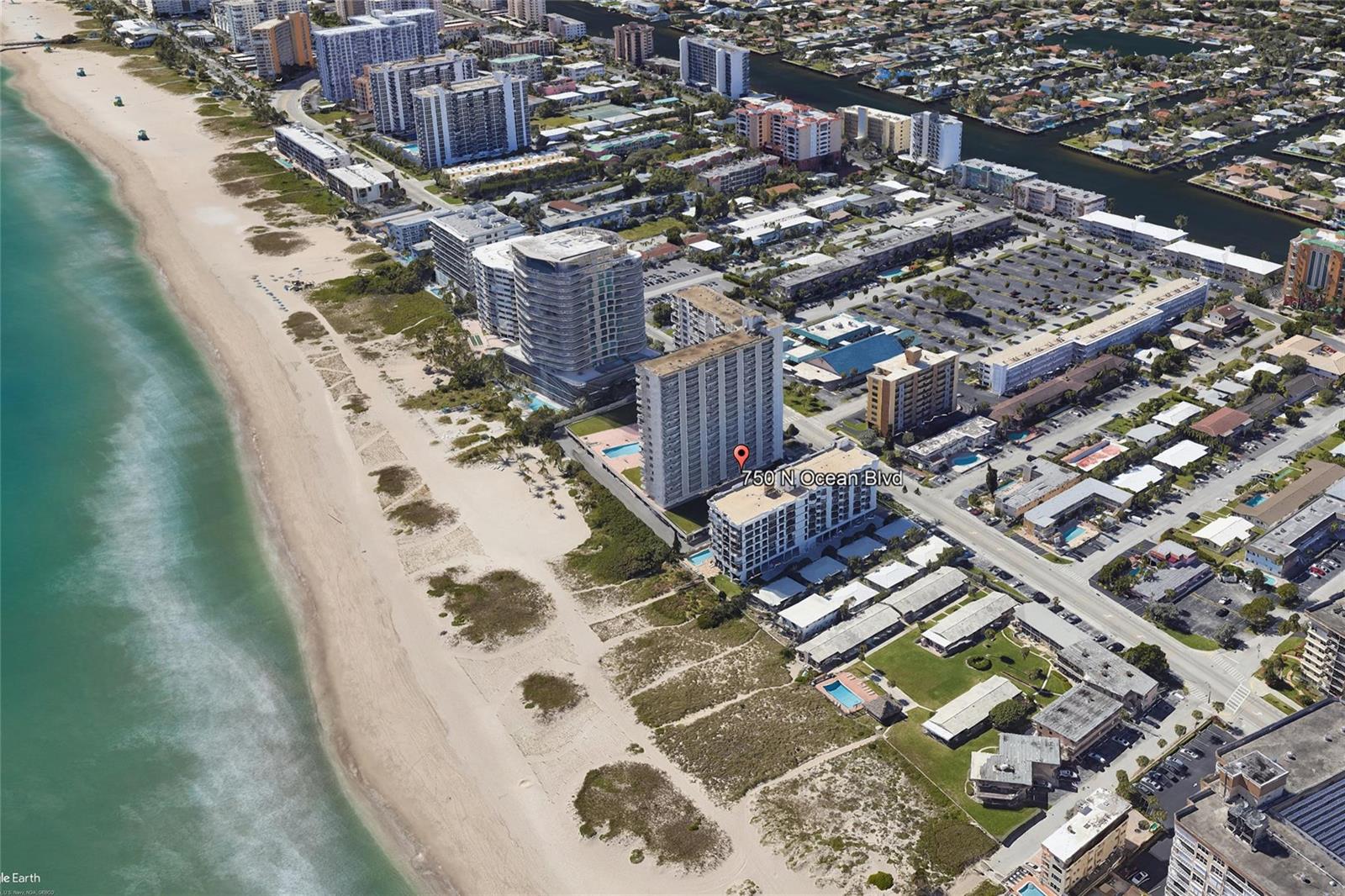 An aerial view shows a high-rise building on a sandy beach next to the ocean — 750 N Ocean Boulevard # 1503, Pompano Beach FL 33062, POMPANO BEACH, FL
