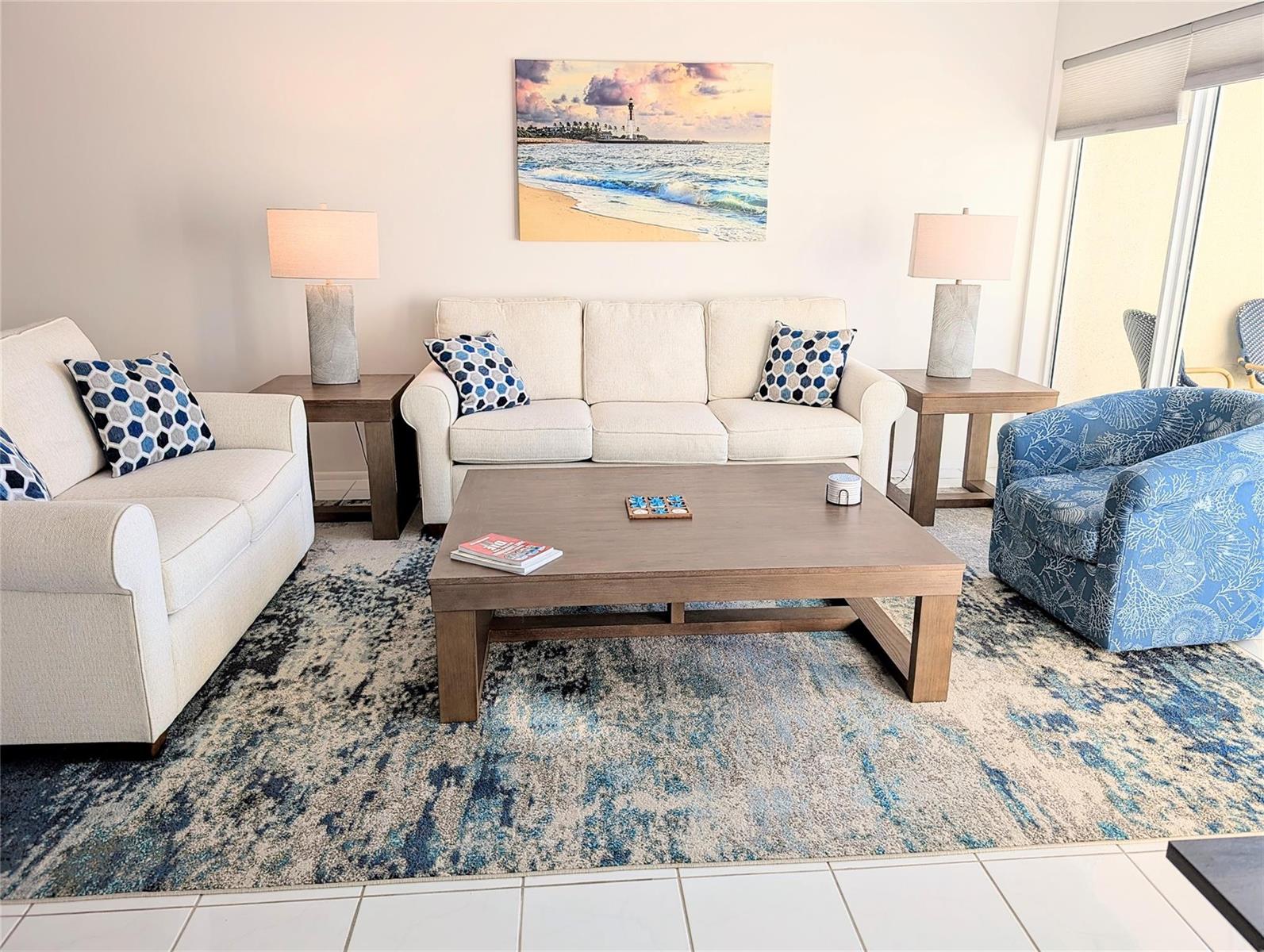 A living room features a beige sofa, a blue patterned armchair, and a large area rug — 750 N Ocean Boulevard # 1503, Pompano Beach FL 33062, POMPANO BEACH, FL