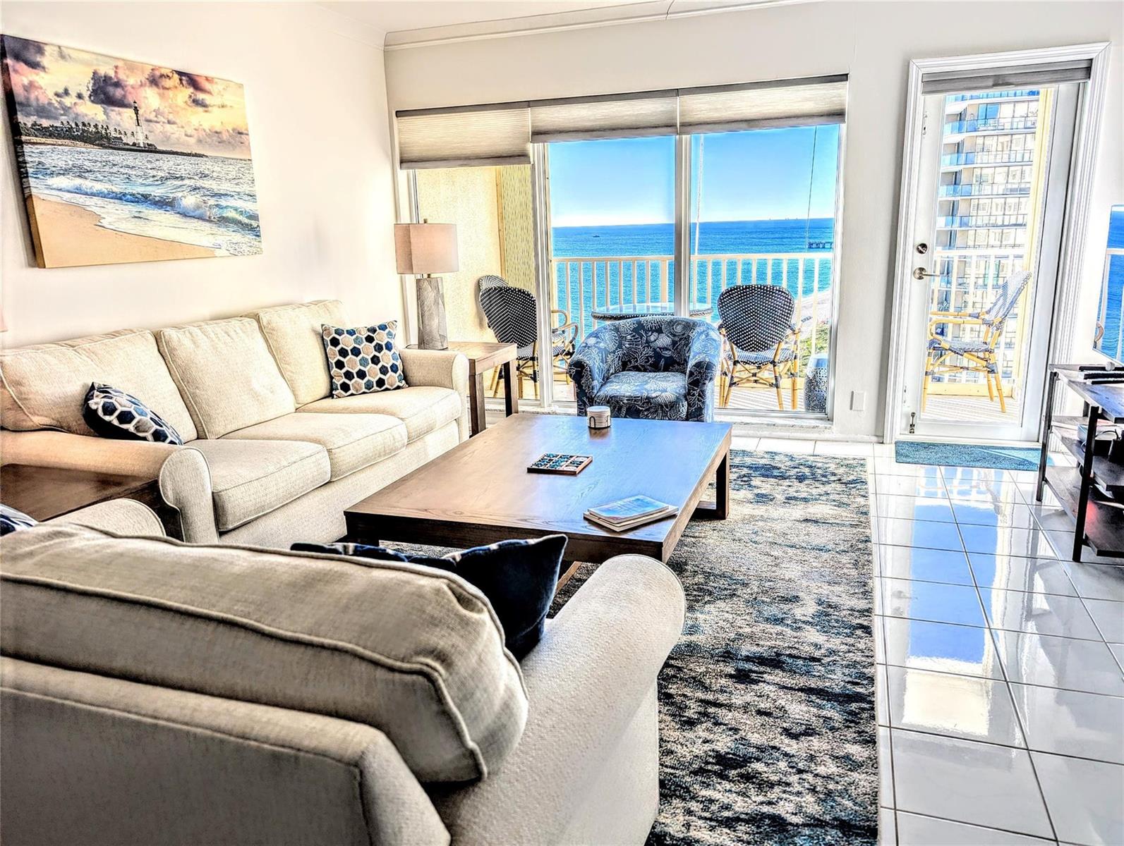 A living room with a beige sofa, coffee table, and sliding glass doors overlooking the ocean — 750 N Ocean Boulevard # 1503, Pompano Beach FL 33062, POMPANO BEACH, FL