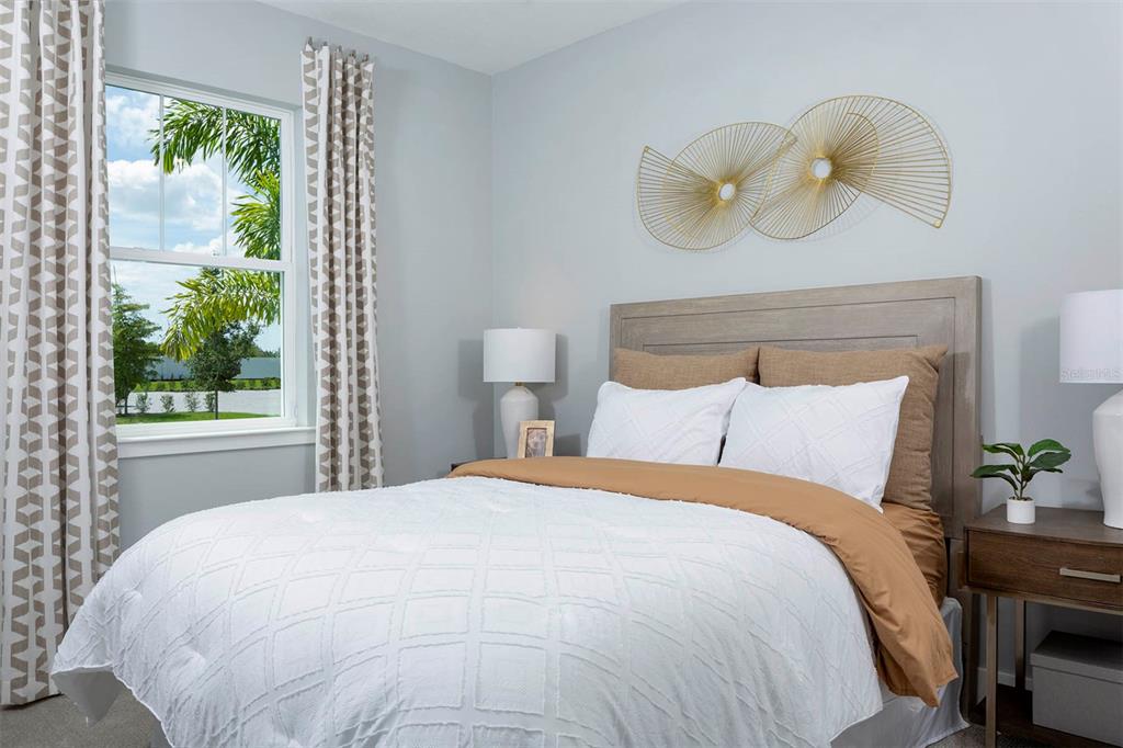 A bedroom features a bed with white bedding, a wooden headboard, and gold wall art — 17760 STILLNESS COURT, VENICE, FL