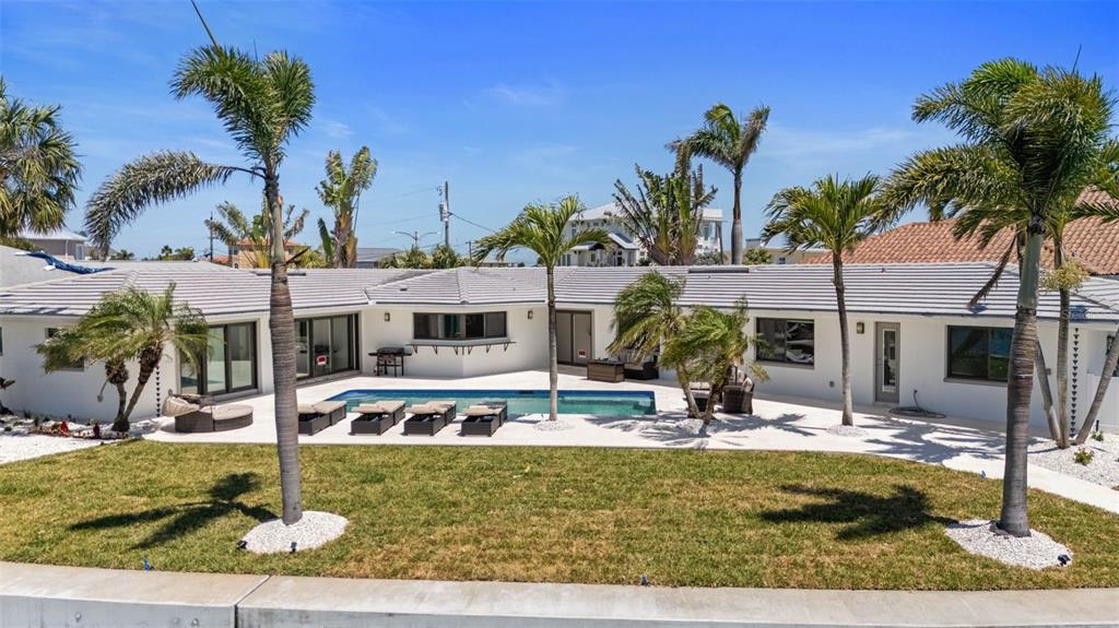 A single-story house with a swimming pool, patio, and palm trees in the backyard — 11050 7TH STREET E, TREASURE ISLAND, FL