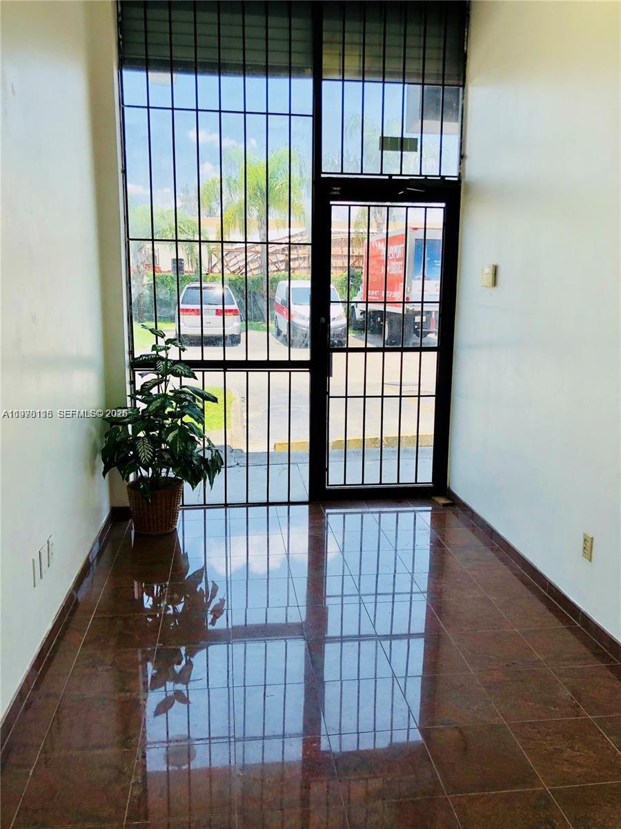 A tiled entryway features a potted plant and a large metal-framed glass door — 6850 NW 77th Ct # 6850, Medley FL 33166, MEDLEY, FL