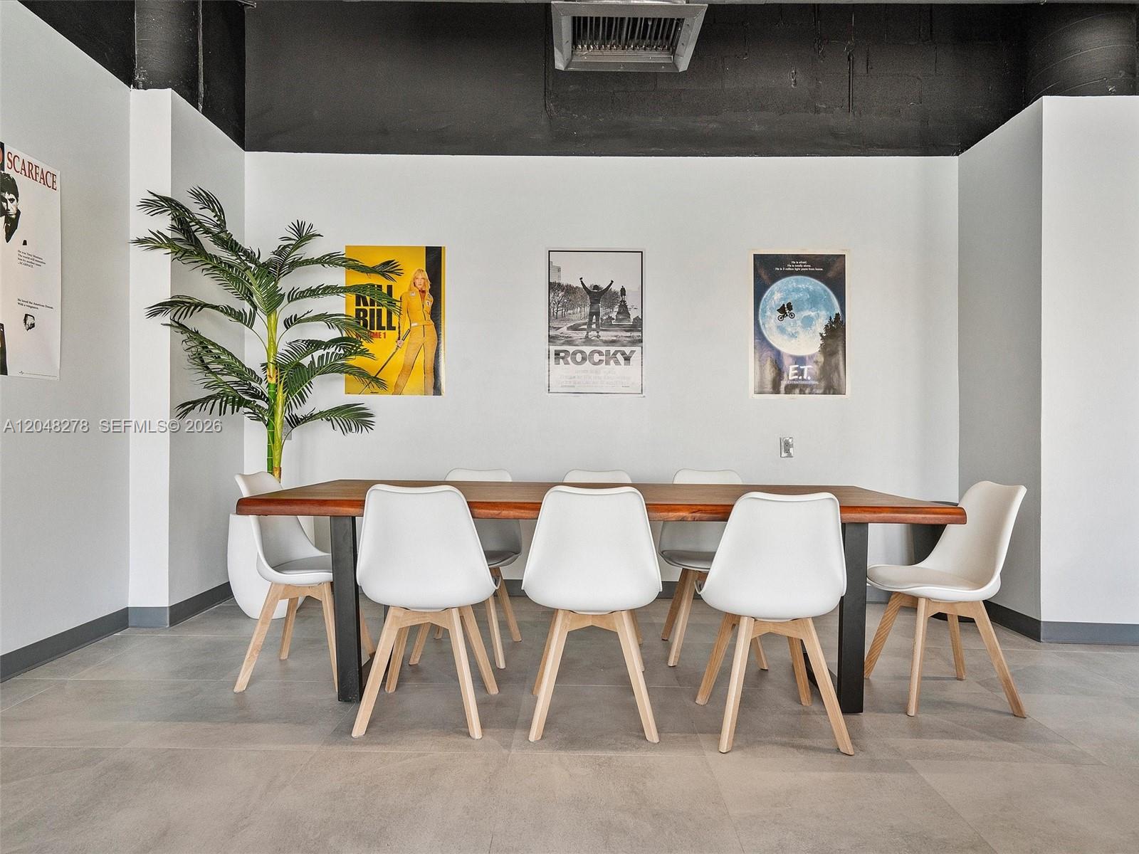 A dining room features a wooden table, six white chairs, and movie posters on walls — 900 SW Bay Dr, Miami Beach FL 33141, MIAMI BEACH, FL