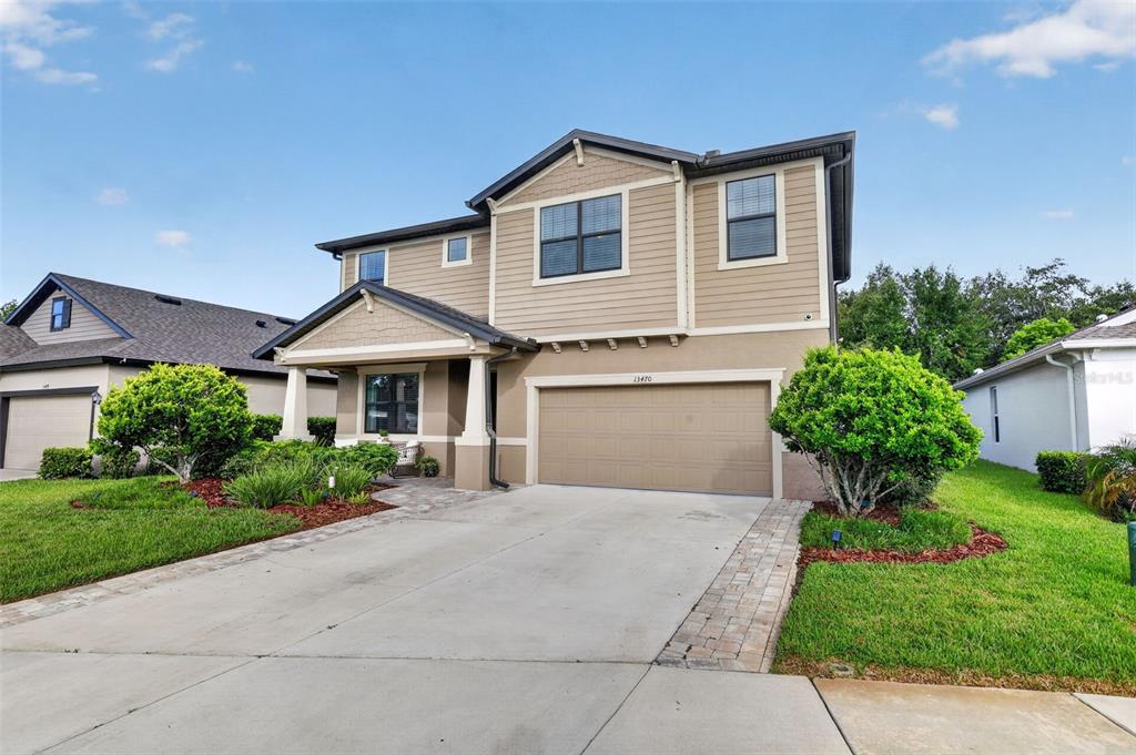 A two-story suburban house with tan siding, a front porch, and an attached garage — 13470 NEWPORT SHORES DRIVE, HUDSON, FL