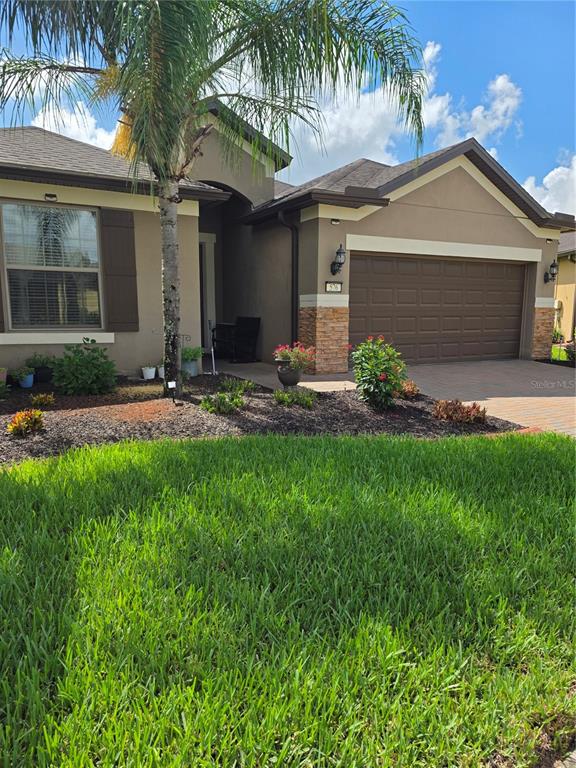 A single-story house with a brown garage, stone accents, and a palm tree in front — 576 CANTABRIA DRIVE, DAVENPORT, FL